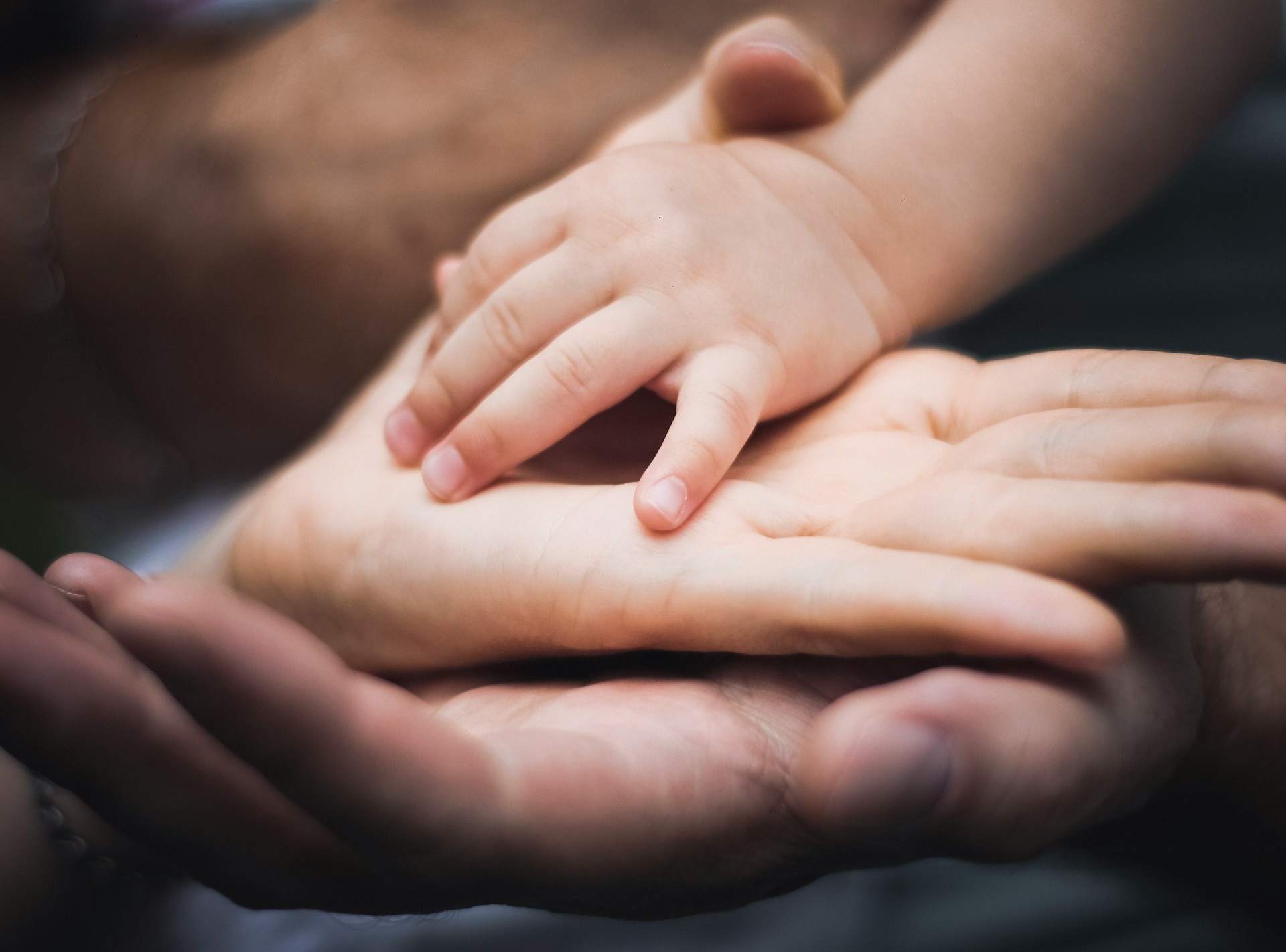 mãos de pais e criança sobrepostas